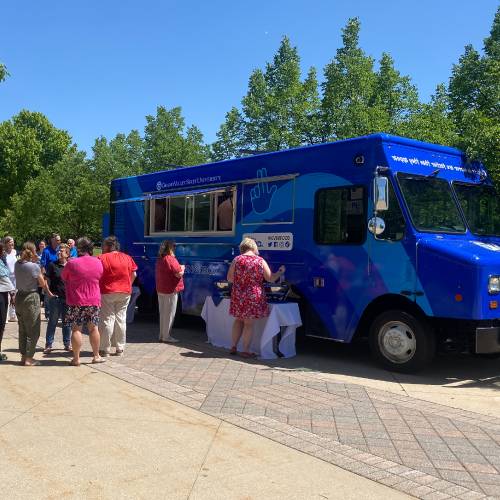 group of people standing next to Louie's Lunchbox food truck on GVSU's campus
